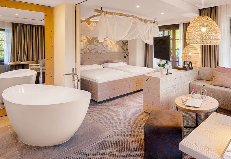 Hotelzimmer mit freistehender Badewanne und Lampenschirmen in Bast